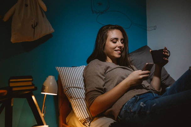 young woman relaxing in her room. using mobile phone - Фото, зображення