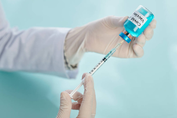 Imagen de cerca de la jeringa de llenado de médico general femenino con vacuna azul contra covid-19 - Foto, imagen