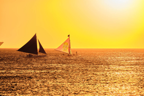 Boracay, Philippines - 23 janv. 2020 : Coucher de soleil sur l'île de Boracay. Voile et autres bateaux traditionnels avec des touristes sur la mer dans le contexte du soleil couchant - Photo, image