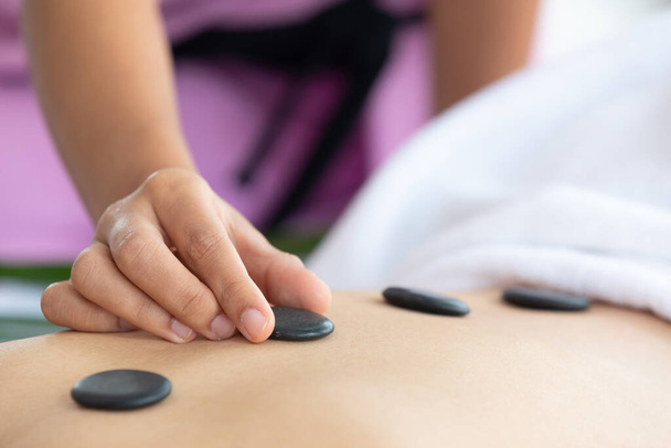 gros plan jeune asiatique masseur putting chaud pierre massage dans spa salon - Photo, image