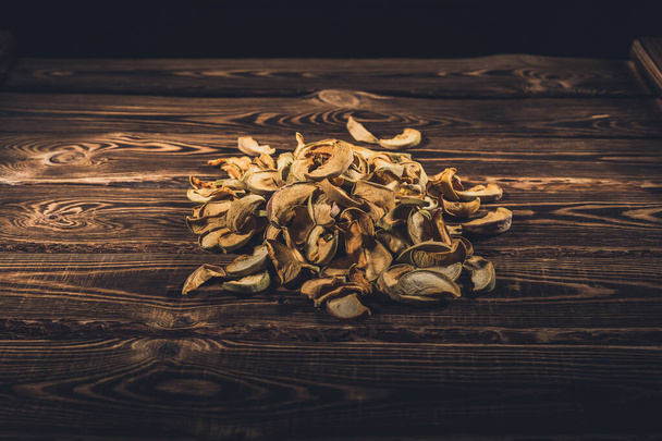 Slices of dried apples on a wooden background. A studio photo with hard lighting. - Photo, Image