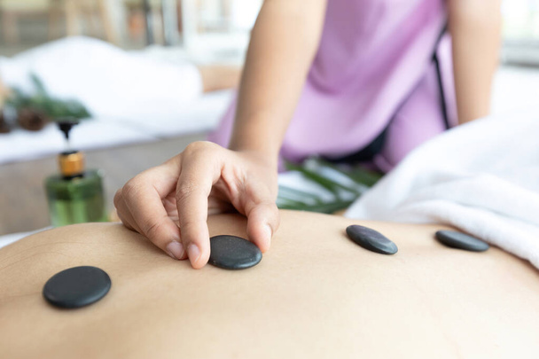 крупним планом молодий азіатський масажист кладе масаж гарячим каменем в спа-салон
 - Фото, зображення