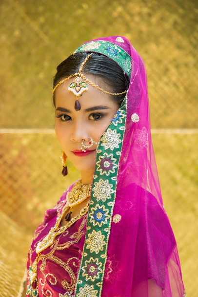 Κοντινό πλάνο πορτρέτο γοητευτική Ασιάτισσα γυναίκα φορώντας ένα παραδοσιακό σάρι με φόντο χρυσό τοίχο. - Φωτογραφία, εικόνα