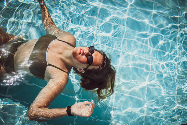 Moda portret wdzięku słodkie dziewczyny w stylowych okularach przeciwsłonecznych pozowanie w basenie podczas wakacji na luksusowym kurorcie. Wesoły plus rozmiar nastolatka cieszy. radosne, pozytywne emocje, letni styl. - Zdjęcie, obraz