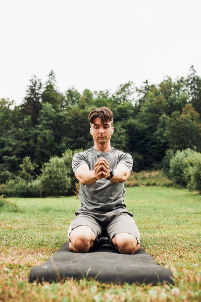 Young man doing exercises outside on grass during his calisthenics workout. Teenager training outdoors - Fotografie, Obrázek