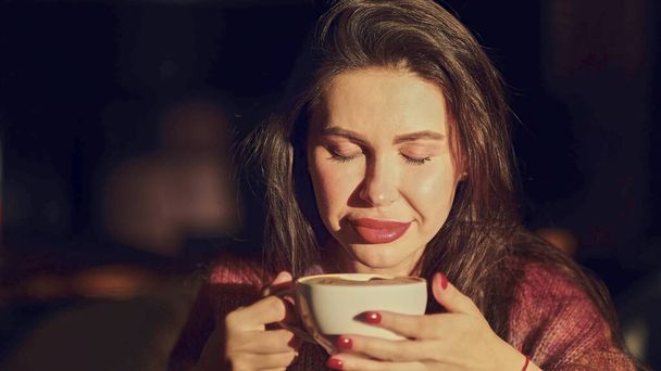 face of young woman relaxing smell of hot coffee. - Foto, imagen