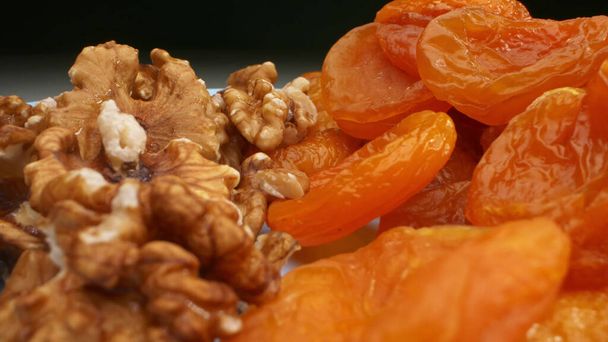 extremely close-up, detailed. walnut kernels and dried apricots on a blue plate - Fotoğraf, Görsel