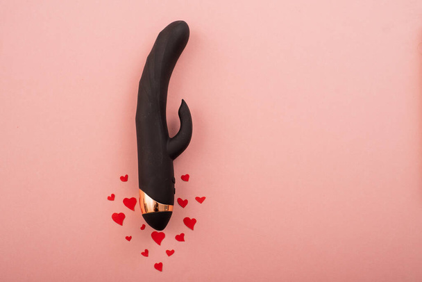 Black clitoral vaginal dildo and hearts on a pink background. Female vibrator as a gift for Valentines Day. Copy space - Foto, Bild