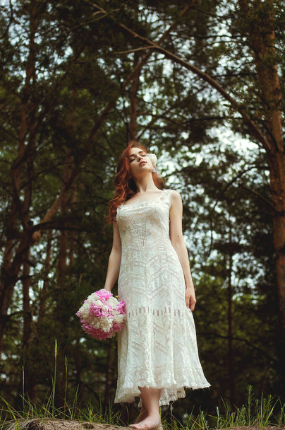 Szabadtéri portré fiatal vörös hajú nő vintage esküvői ruha nagy csokor rózsaszín bazsarózsa. Női nap. Női tavasz, nyári divatkoncepció. Esküvő napja. - Fotó, kép