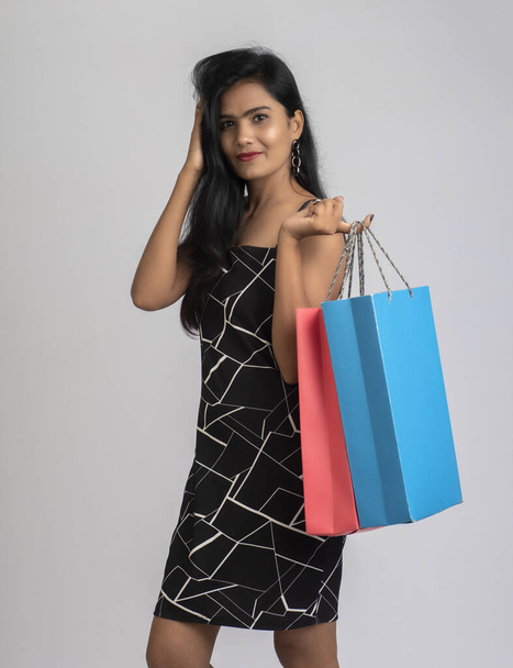 Beautiful young girl holding and posing with shopping bags on a grey background - Foto, Imagem