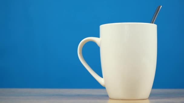 taza blanca con café sobre un fondo azul - Metraje, vídeo