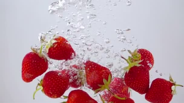 Reife Erdbeeren fallen durch das Wasser. Licht im Hintergrund. Zeitlupe. - Filmmaterial, Video