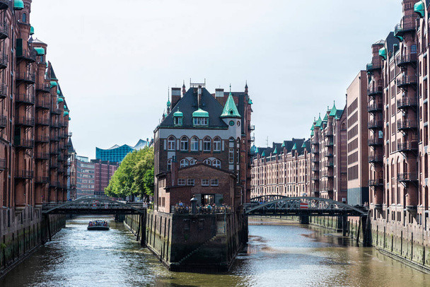 Wasserschloss Speicherstadt Restoranı 'nın etrafında insanlar ve eski depoları HafenCity, Hamburg, Almanya' da bir kanalın yanındaki ofislere ve dairelere dönüştürüyor.  - Fotoğraf, Görsel