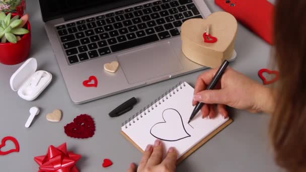 Joven mujer escribiendo una tarjeta te amo mientras envuelve regalo de San Valentín  - Metraje, vídeo