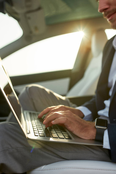Laptop in hands of working businessman in car - Foto, Bild