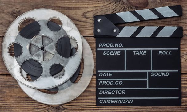 Movie clapper board and film reel on wooden background. Cinema industry, entertainment. Top view - Photo, Image