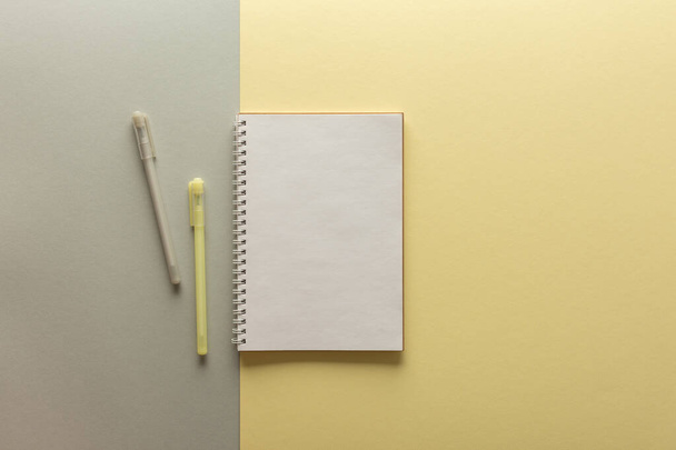 灰色と黄色の背景、ノートブックとペンの上にオープンスパイラルノートパッドは、繊維紙の上に横たわる、今年の流行の色でフラットレイコンセプト黄色と灰色 - 写真・画像