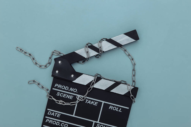Film clapperboard zabalený v ocelovém řetězu na modrém pozadí. Zákaz filmování. Horní pohled - Fotografie, Obrázek