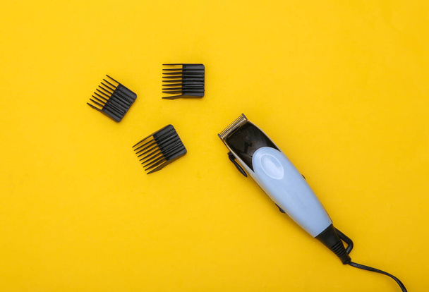 Haarschneidemaschine mit Befestigungen auf gelbem Hintergrund. Ansicht von oben - Foto, Bild