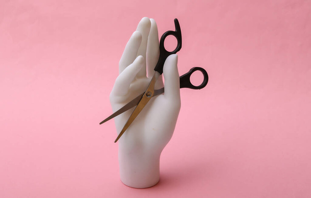Mannequin Hand hält Haarschere auf rosa Hintergrund. Schönheitskonzept Minimalismus - Foto, Bild
