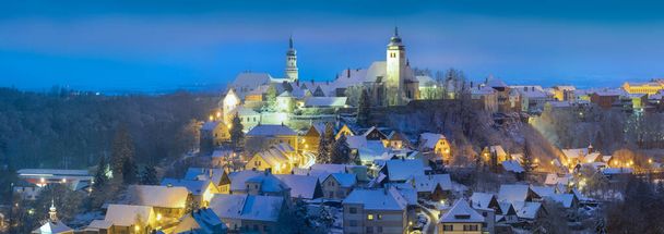 Winternachtansicht in Nove Mesto nad Metuji, in der Nähe von Hradec Kralove, Tschechien. Stadtpanorama mit der Burg auf dem Gipfel des Hügels, gefrorenen Bäumen. Das Zentrum steht unter Denkmalschutz. - Foto, Bild