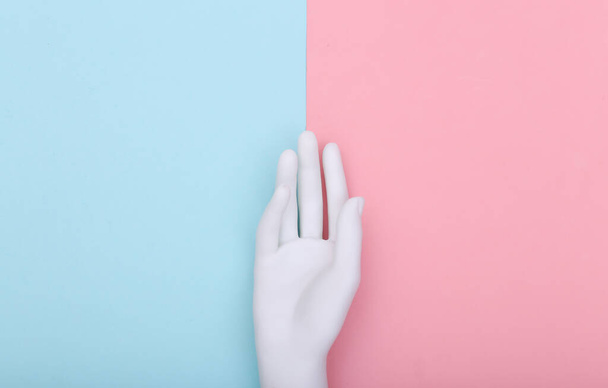 Bílá figurína ruka na modro-růžové pastelové pozadí. Minimalismus. Horní pohled. Plocha - Fotografie, Obrázek