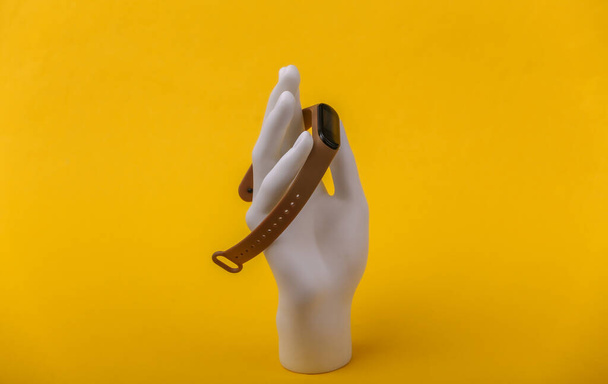 Brazalete de mano maniquí blanco con sujeción inteligente sobre fondo amarillo. - Foto, imagen