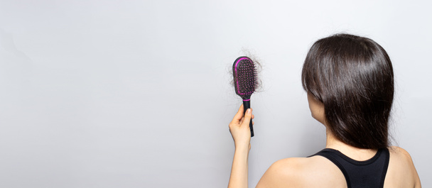 The girl is holding a hairbrush with lost hair. Hair loss, care and treatment. Trichologist, trichology. Banner with place for text copy space - Photo, Image