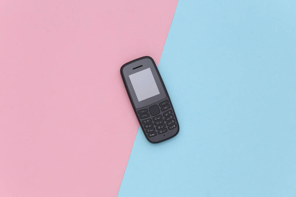 Drukknop telefoon op een blauw-roze pastelachtergrond. Bovenaanzicht - Foto, afbeelding