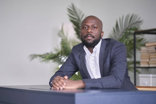 Πορτρέτο ενός Αφροαμερικανού επιχειρηματία στο γραφείο. σοβαρή έκφραση προσώπου, ο νεαρός άνδρας συλλέγεται πριν από μια δοκιμή ή συνέντευξη - Φωτογραφία, εικόνα