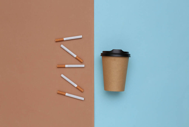 Cattive abitudini. Sigarette e tazza di caffè su sfondo blu marrone - Foto, immagini