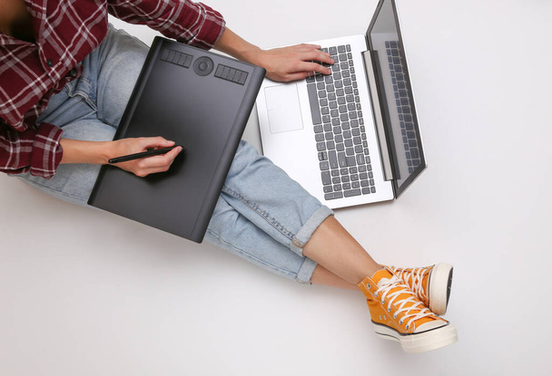 Графічний дизайнер або фотограф. Жінка працює з графічним планшетом і ноутбуком, сидячи на білому тлі. Фріланс, онлайн концепція роботи. Вид зверху
 - Фото, зображення