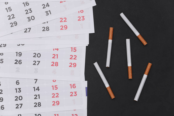 Pára de fumar. Calendário mensal e cigarros em fundo preto - Foto, Imagem