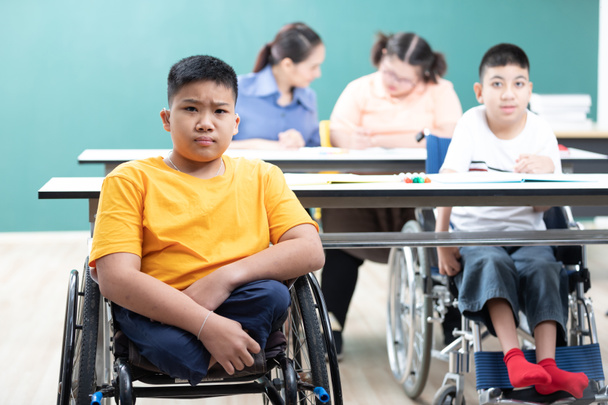 portré ázsiai fogyatékkal élő gyermekek (elveszett lábak) ül egy kerekesszékben az osztályteremben - Fotó, kép