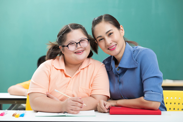 portrait asian disabled child or down syndrome child and woman teacher helping in classroom - Фото, зображення
