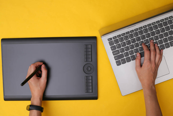 Sarı arka planda grafik tablet ve dizüstü bilgisayarla çalışan kadın grafik tasarımcı veya rötuş makinesi - Fotoğraf, Görsel