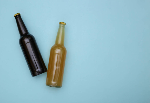 Bottle of light and dark beer on a blue background. Copy space - 写真・画像