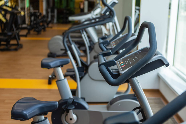 Großaufnahme von Fitness-Fahrrädern im modernen Fitnessstudio-Innenraum - Foto, Bild