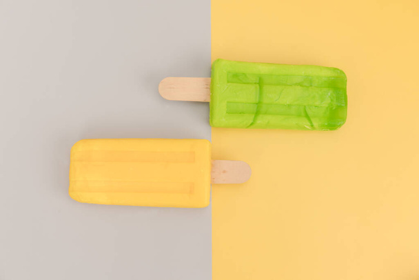 Ice cream stick on gray and yellow background. - Foto, afbeelding