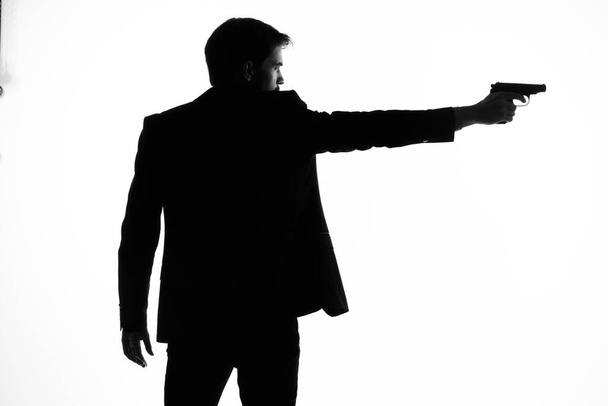 sombra de un hombre con un arma en sus manos apuntando al fondo de la luz del crimen detective - Foto, imagen