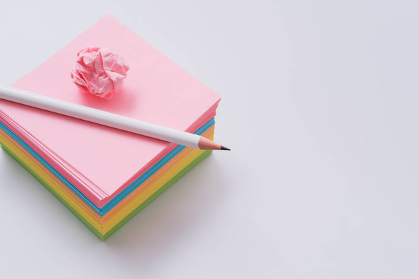 Stack of multi-colour notepaper with white pencil. Thinking and searching for ideas concept - Фото, изображение