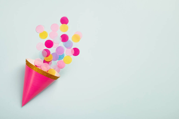 Карнавальна шапка з барвистим паперовим конфетті на світло-блакитному тлі. День народження, карнавальна або ювілейна листівка. Вид зверху, плоский простір, простір копіювання
 - Фото, зображення