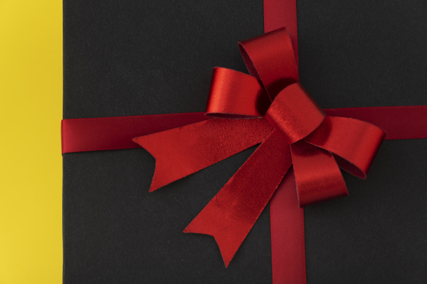 Big red bow on black box close up. Elegant gift - Foto, afbeelding