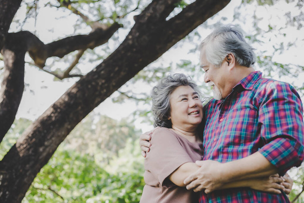 Szczęśliwa para seniorów Dziadek i babcia objęli się miłością i uśmiechniętymi twarzami pod drzewem w parku. Starszy mąż przytulić starą żonę i cieszyć się życiem ze szczęścia Opieka zdrowotna i ubezpieczenie - Zdjęcie, obraz