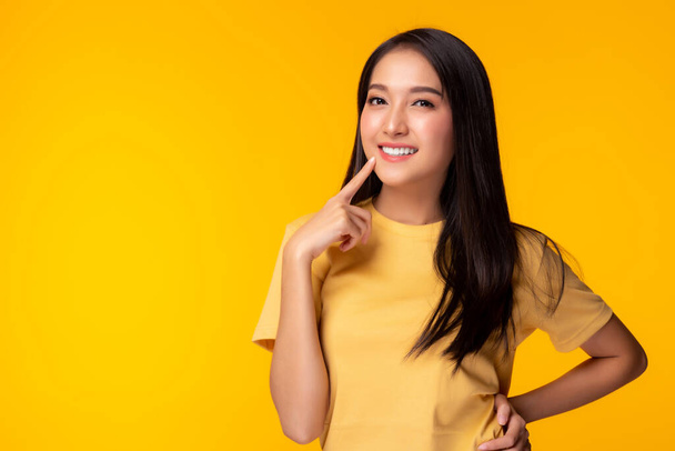 Портрет молодой азиатской женщины с улыбкой Красивая девушка носить желтую футболку с желтым фоном копировать пространство в студии довольно азиатская женщина получить уверенный Красивая женщина имеет длинные волосы Милая леди получить счастливым - Фото, изображение