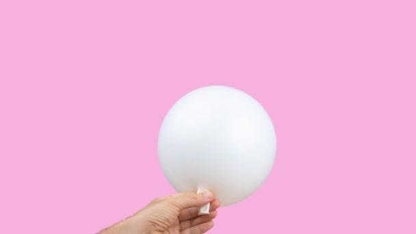 Weißer Luftballon wird vor rosa Hintergrund gesprengt - Filmmaterial, Video