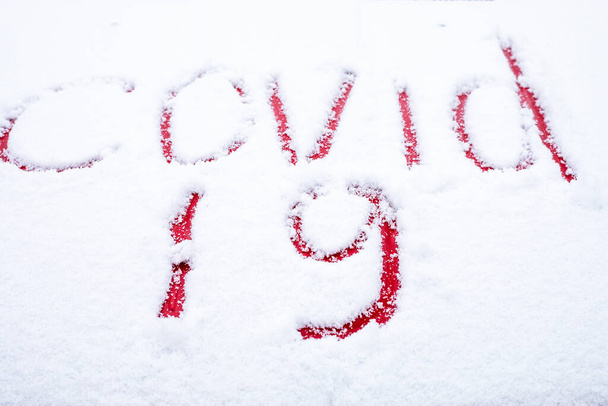 covid -19 napisane palcem w śniegu na masce czerwonego samochodu, blokada, mutacja wirusa - Zdjęcie, obraz