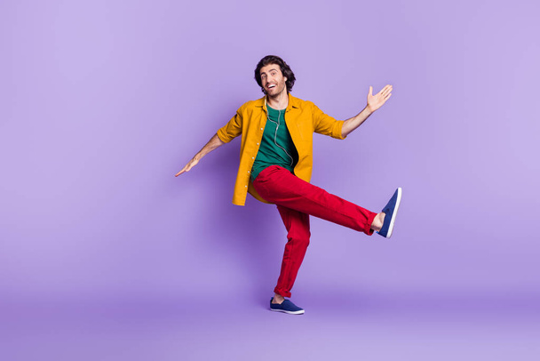 Full length photo portrait of man dancing kicking standing on one leg isolated on vivid violet colored background - Photo, image