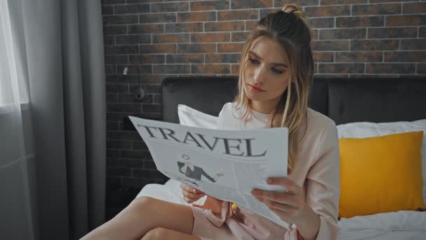 χαρούμενη γυναίκα διαβάζει ταξιδιωτική εφημερίδα στο δωμάτιο του ξενοδοχείου  - Πλάνα, βίντεο