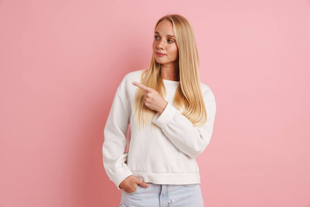 Caucasian beautiful girl looking and pointing finger aside isolated over pink background - Photo, Image